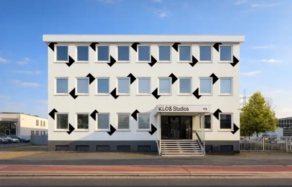 Fassade der KLOZ Studios mit Logo der Bohland Design Stiftung und typografisch gekennzeichnetem Eingangsbereich, blauem Himmel und Straße im Vordergrund.